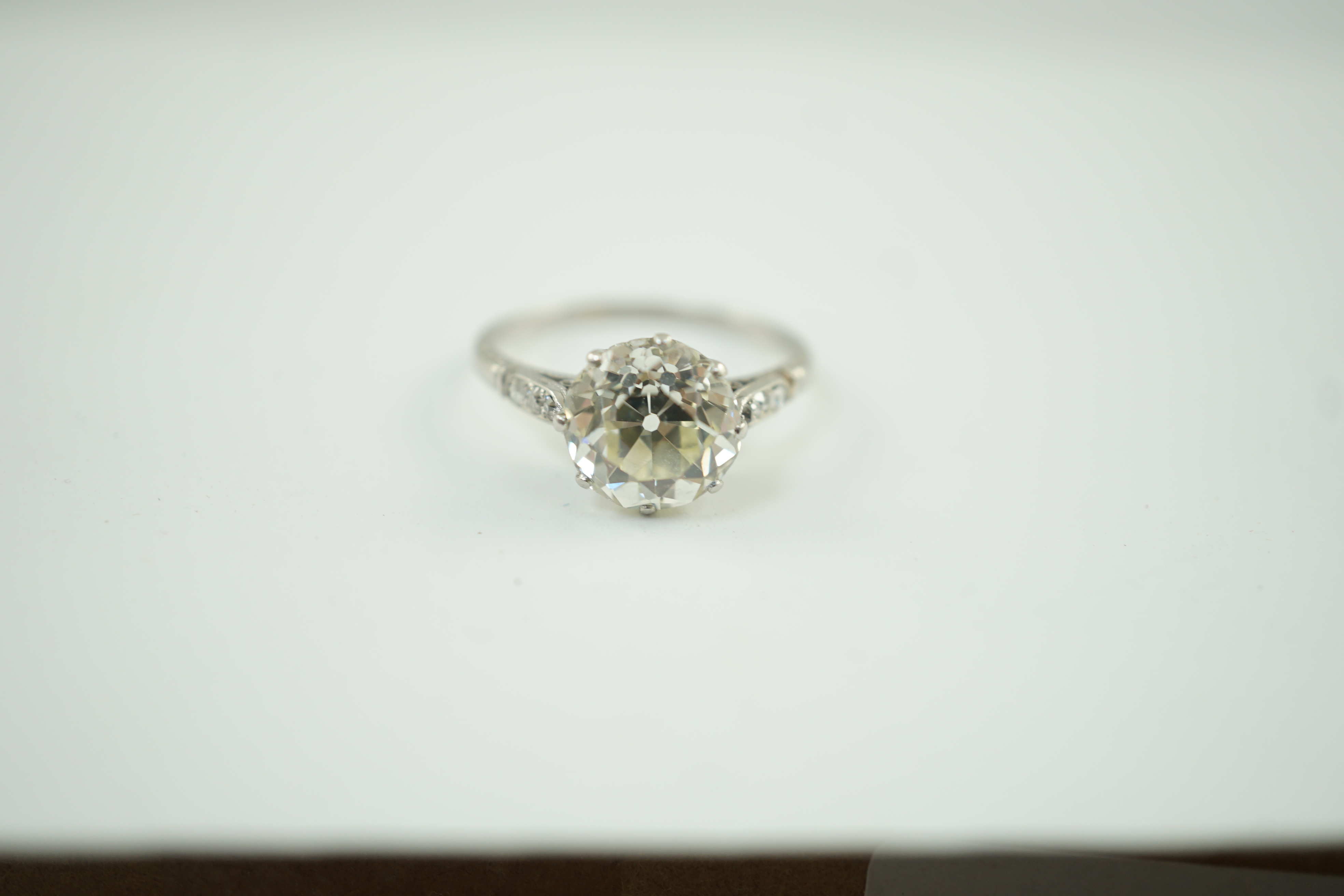 A mid 20th century platinum and single stone diamond ring, with six stone diamond chip set shoulders